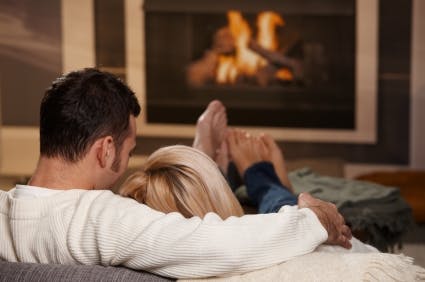 Couple comfortably sitting next to a fireplace